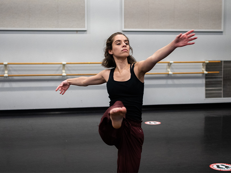 A student works on choreography for a dance research project inside a dance studio.