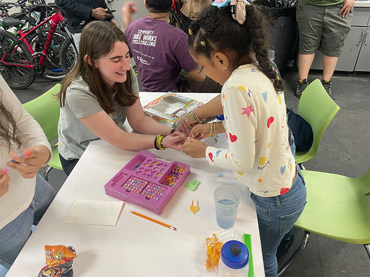 A college student works with a young girl at a youth bike organization.