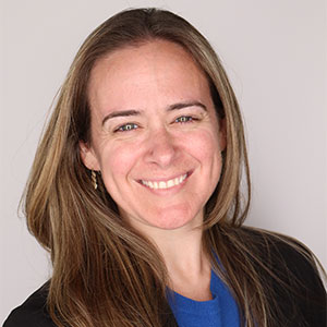 A headshot photo of a smiling woman with long brown hair.