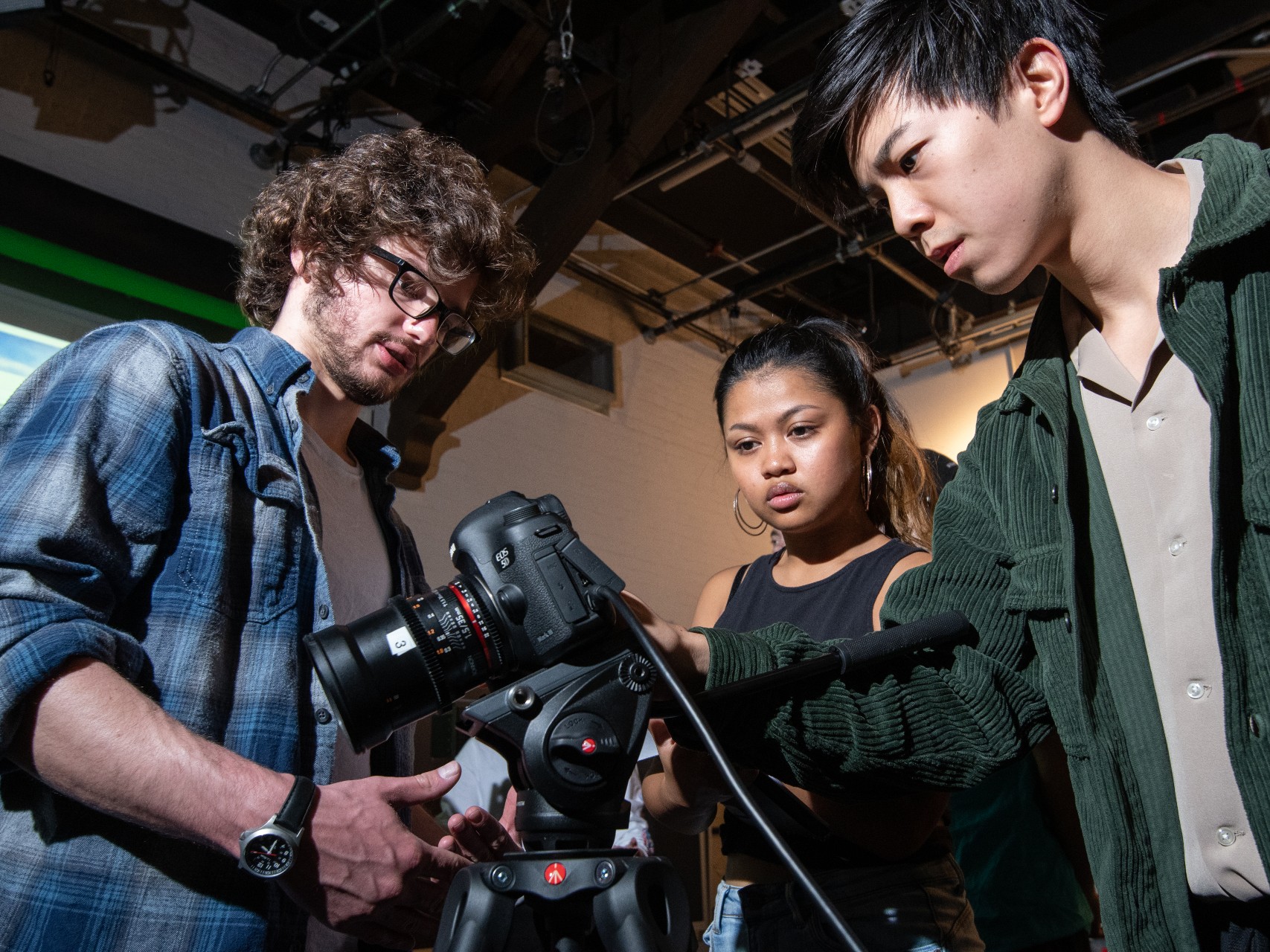 Students examine camera equipment as part of their classroom learning experience.
