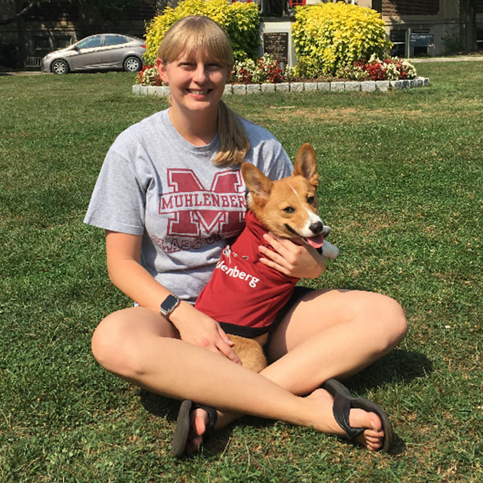 Alumni sitting in grass with dog