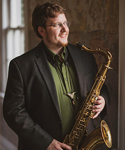 Dan Wilkins profile image standing against wall with natural light appearing through window.