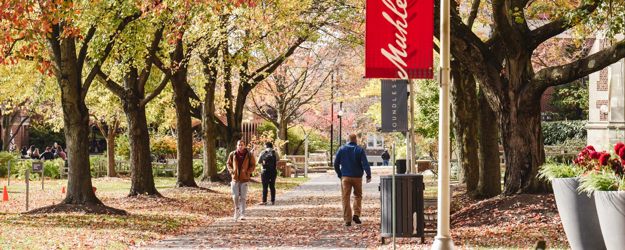 A few students walking along pathway underneath signage that reads 