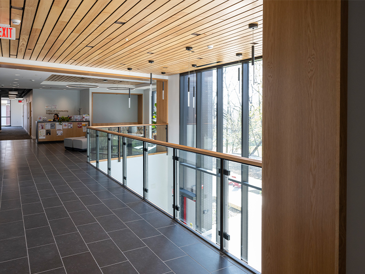 A hallway, brightened by natural light from a wall of windows, inside the Fahy Commons building.