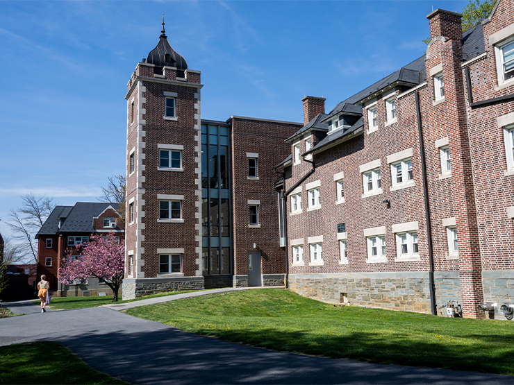 Tall brick residence halls sit under a blue spring sky.