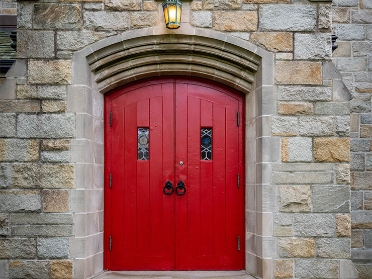 Two red wooden doors set in a stone structure.