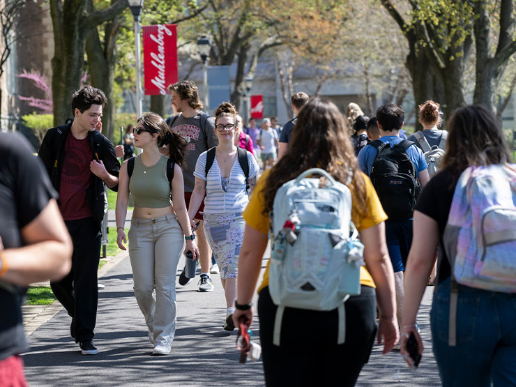 A college walkway lined with hanging red banners that read