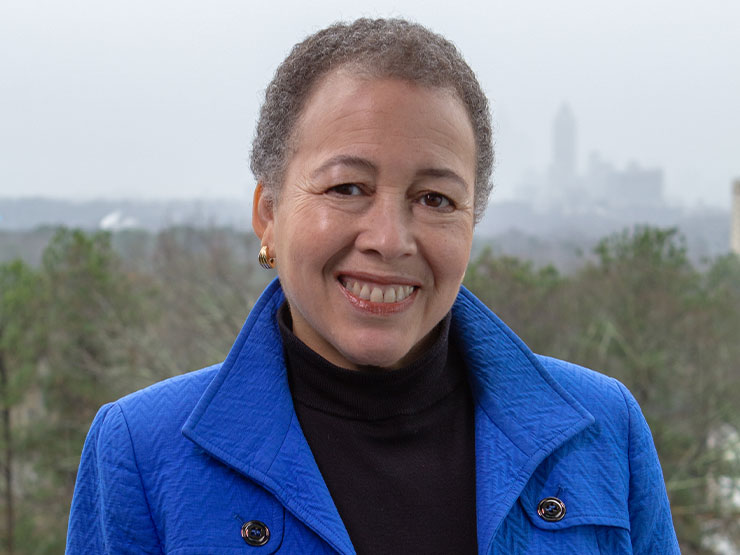 Beverly Tatum, wearing a bright blue jacket, smiles at the camera.