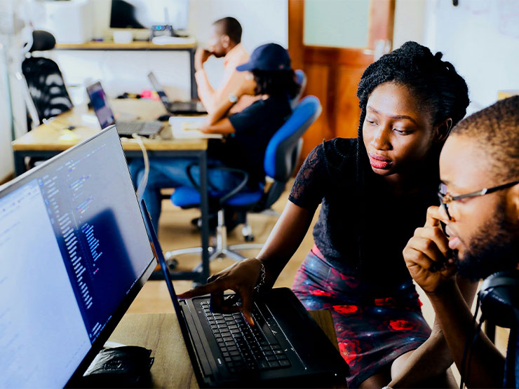 Two adult students work together on a laptop.