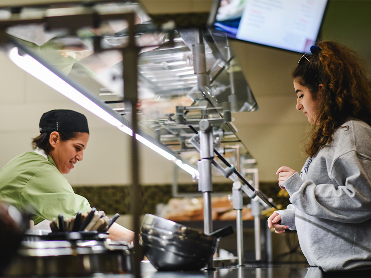 A dining worker serves a student in the cafeteria of Wood Dining Commons.