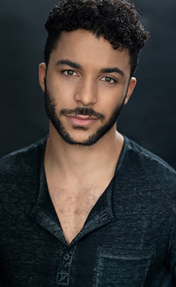 A headshot of Jakeim Hart wearing a black T-shirt in front of a dark background