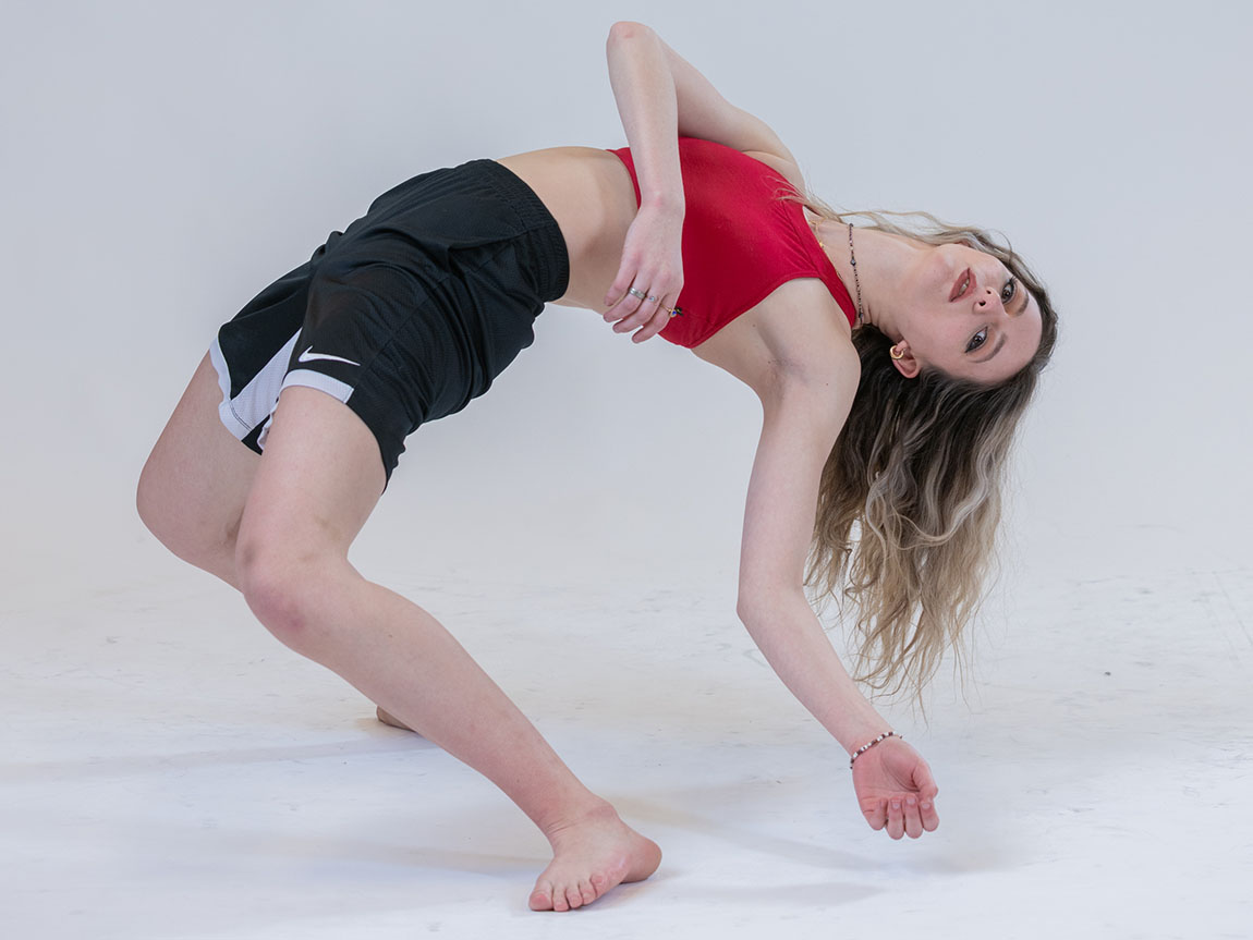 A college student in athletic clothing leans back in a dance posture
