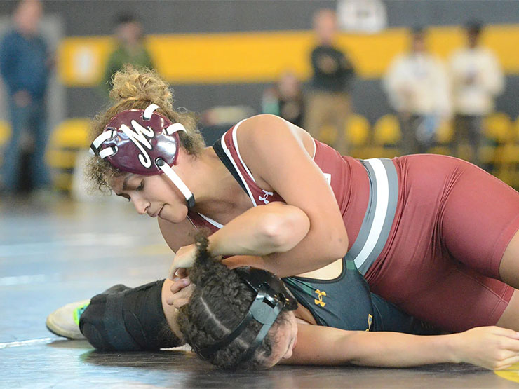 A pair of college women's wrestlers spar on the mat.