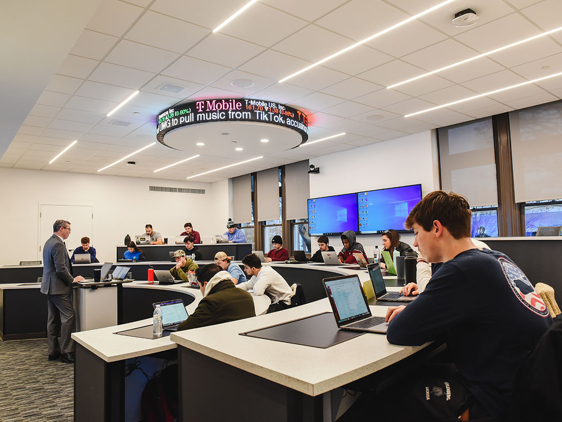 Students take classes in a newly renovated finance lab with stock price displays on the ceiling.