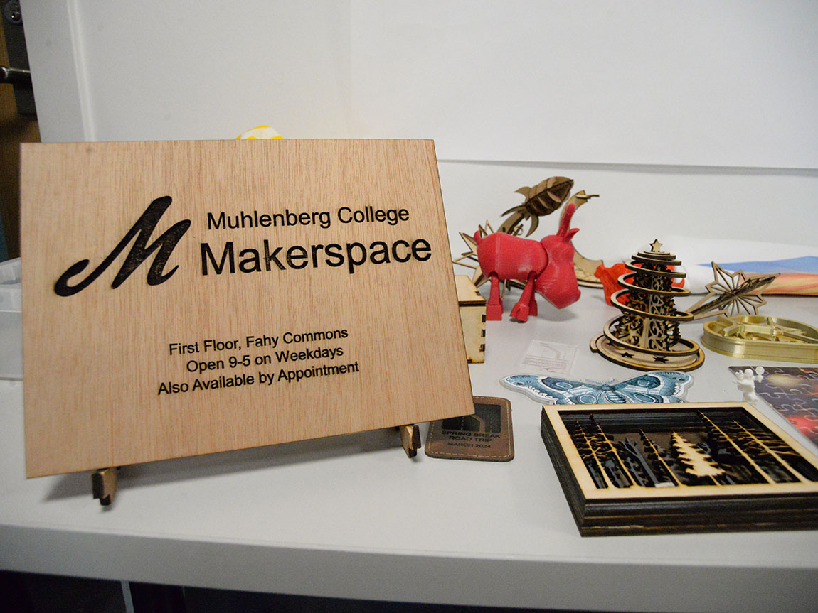 A laser cut wood sign says Muhlenberg College Makerspace, First Floor, Fahy Commons, Open 9-5 on weekdays, also available by appointment