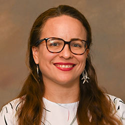 A headshot of Lilianne Lugo Herrera, who has long brown hair and glasses