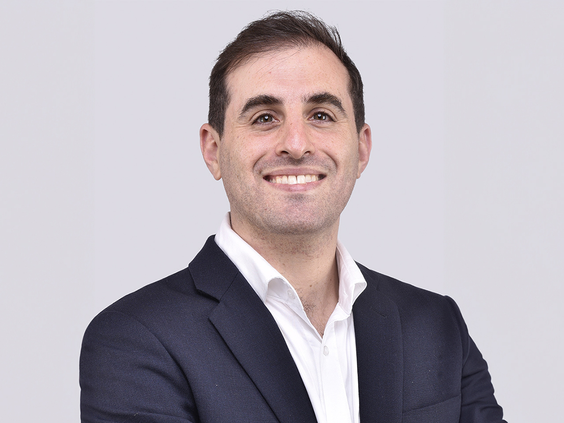 A headshot of a man in a blazer and white shirt