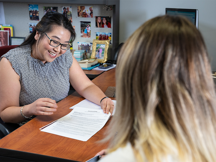 A woman shows paperwork to a person in the foreground.