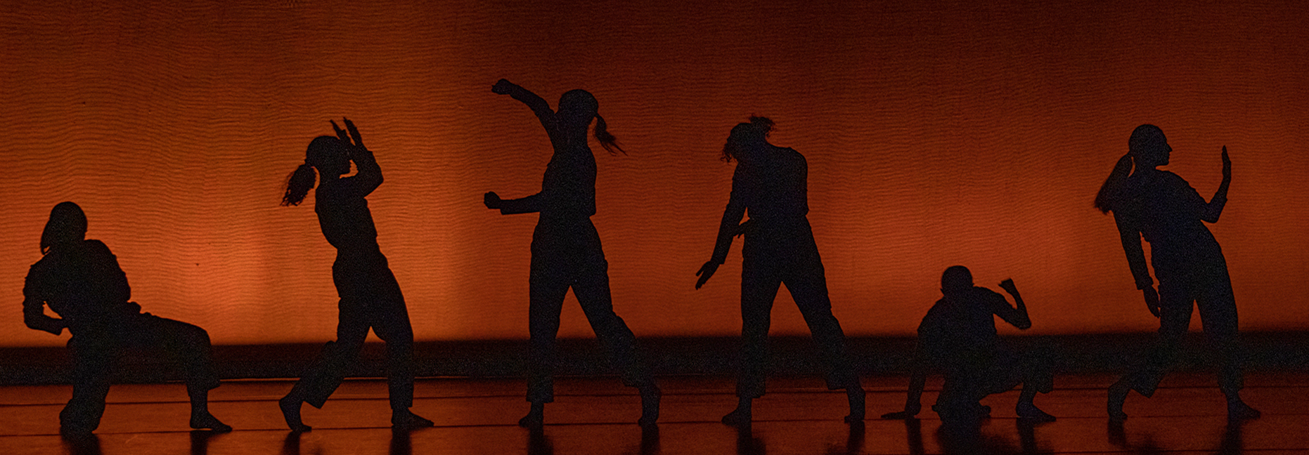 Silhouetted dancers on an orange background