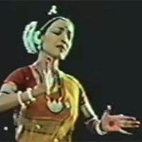 An Indian woman in traditional dress dances.