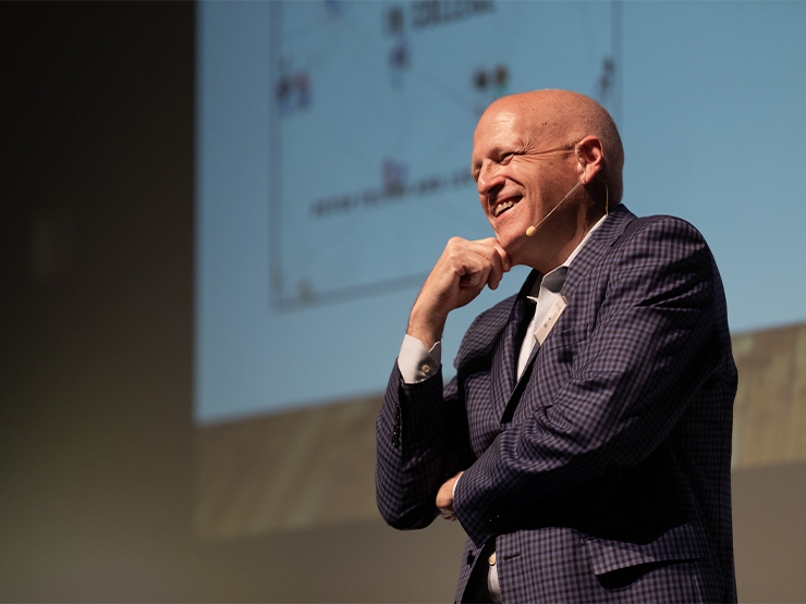 A man in a suit speaks to an audience.