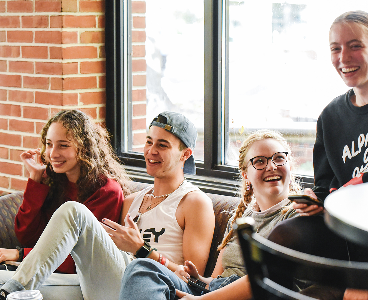 A group of students, smiling and laughing, squeeze together on a couch.