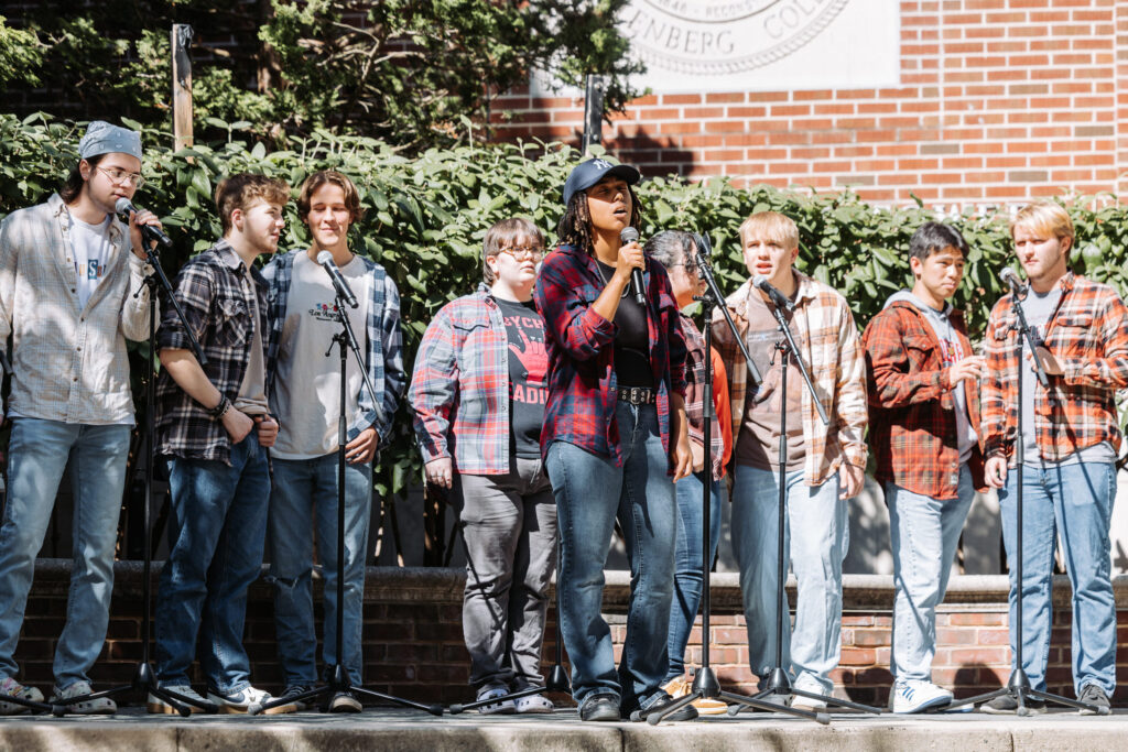 A group of college students wearing plaid sings outside