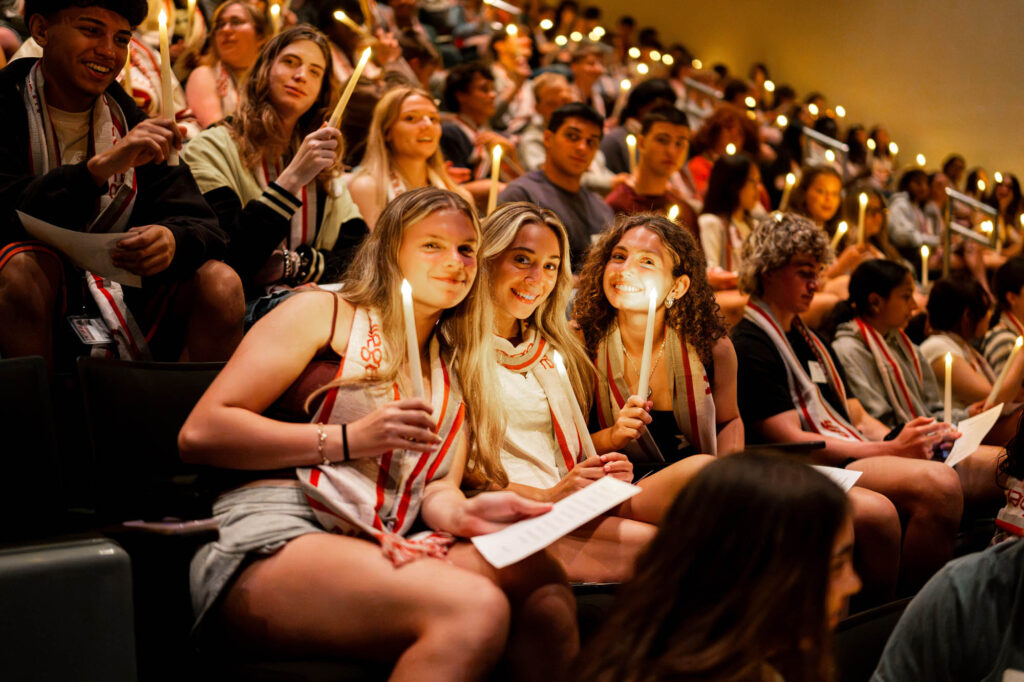 Three new Muhlenberg College students pose with battery-operated candles