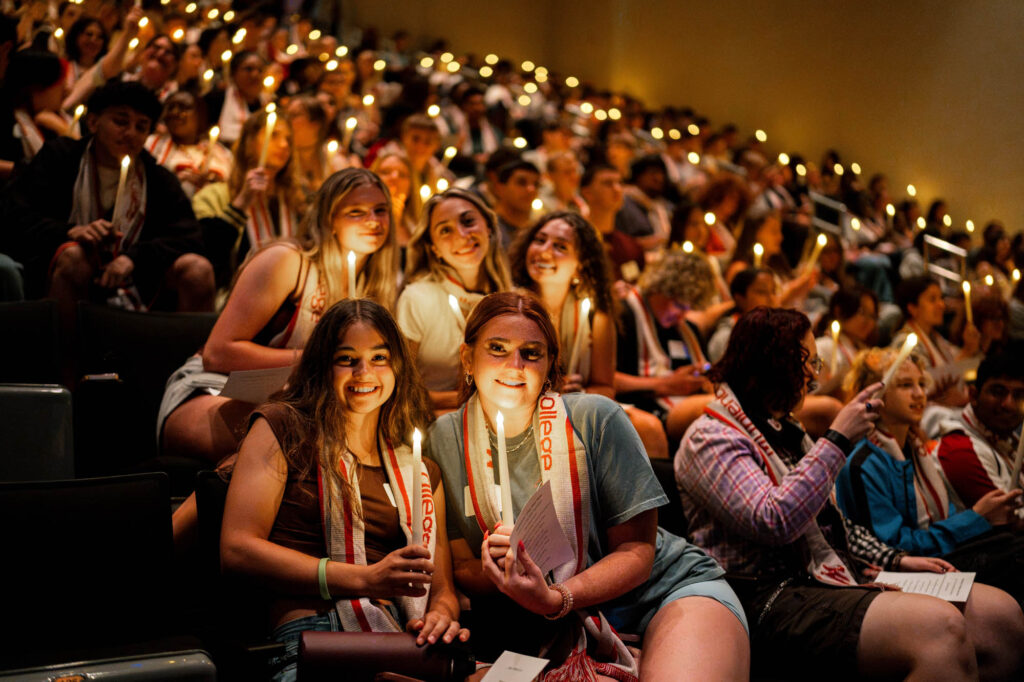 New Muhlenberg College students pose with battery-operated candles in a full auditorium