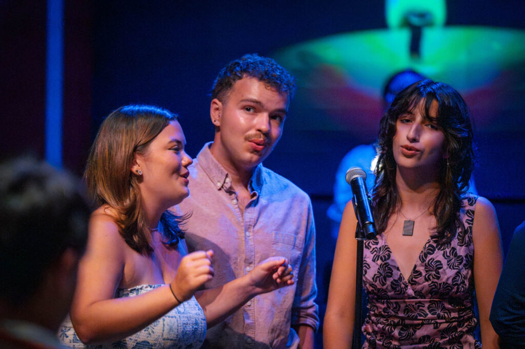 Three Muhlenberg College students sing near a microphone