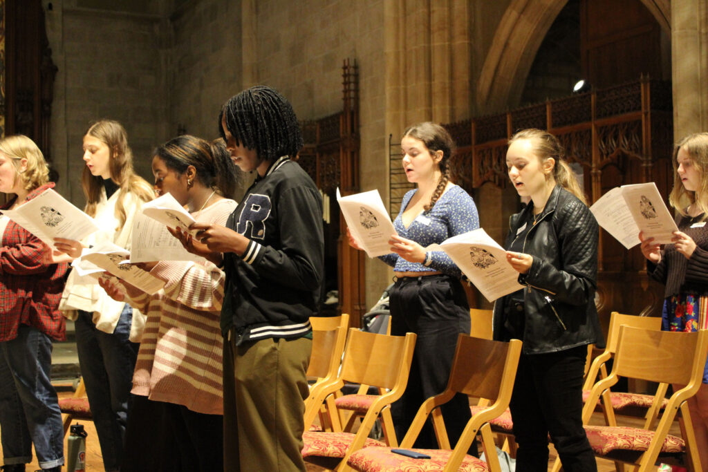 A group of college students sing together in a chapel