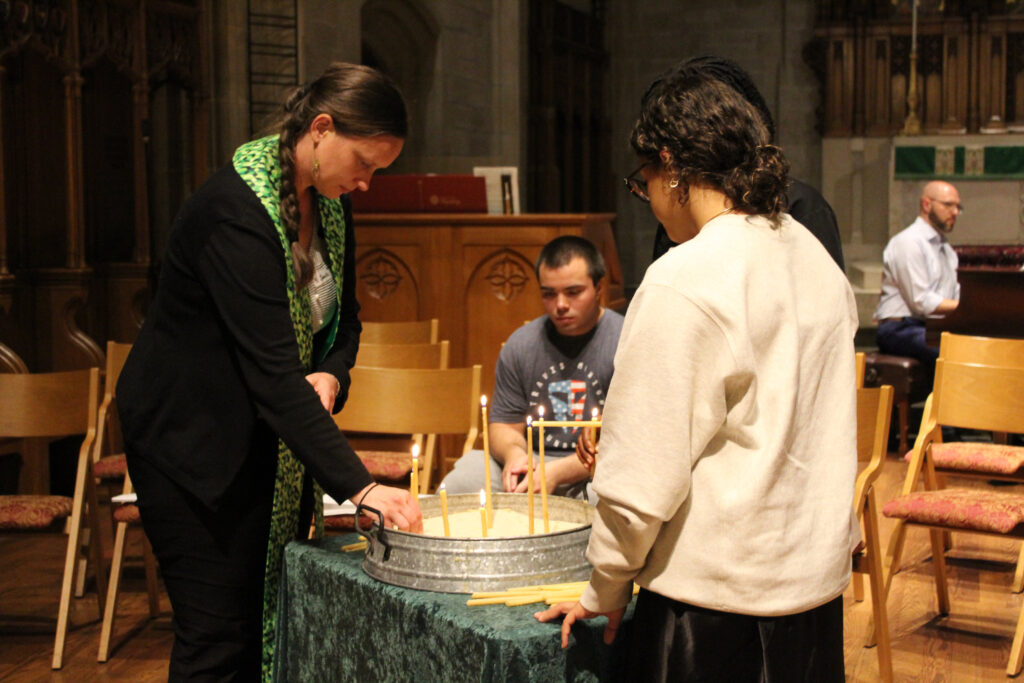 A pastor and a college student light candles in a chapel