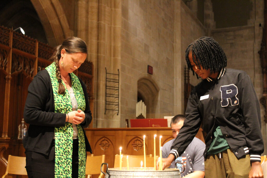 A pastor and a college student light candles in a chapel