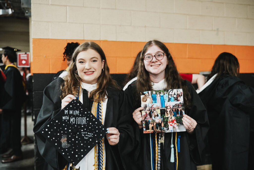 Two college graduates show their caps