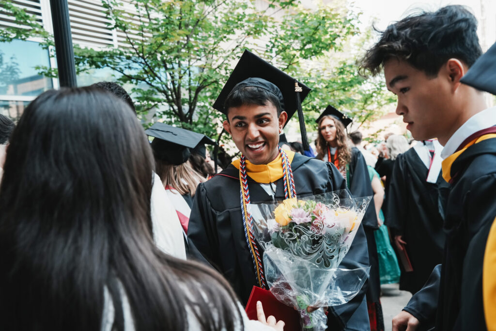 A college graduate holds flowers after commencement