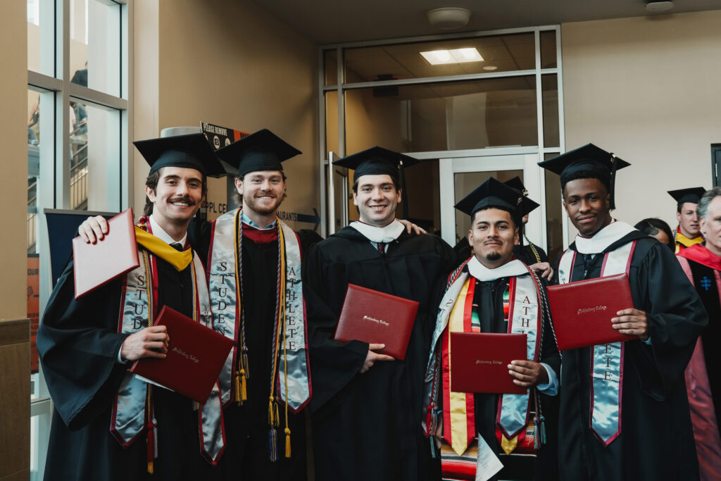 Five college graduates pose with their diplomas after commencement