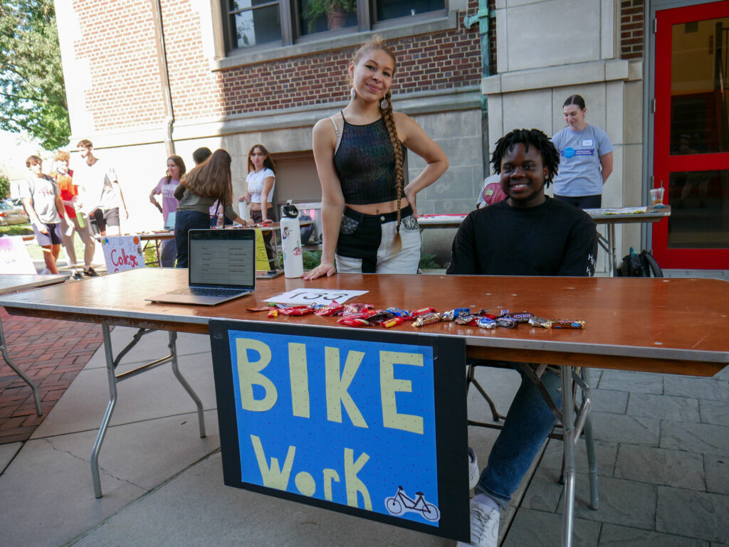Two college students at a table with a sign that says BIKE Work
