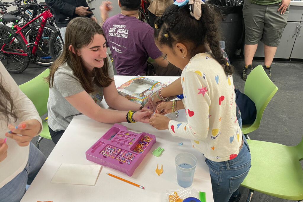 A college student does a craft project with a young girl
