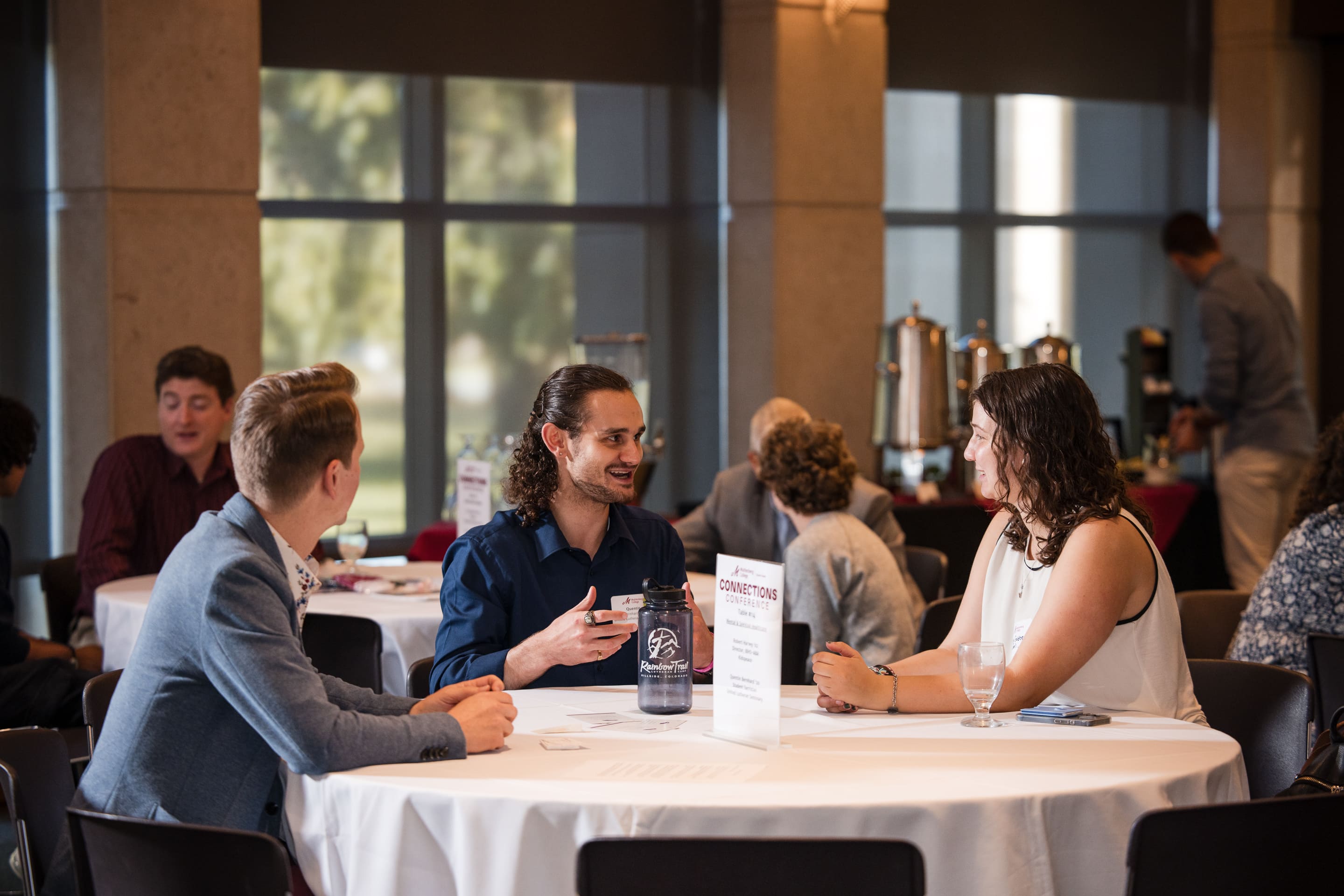 A two men talk to college students during a roundtable networking event