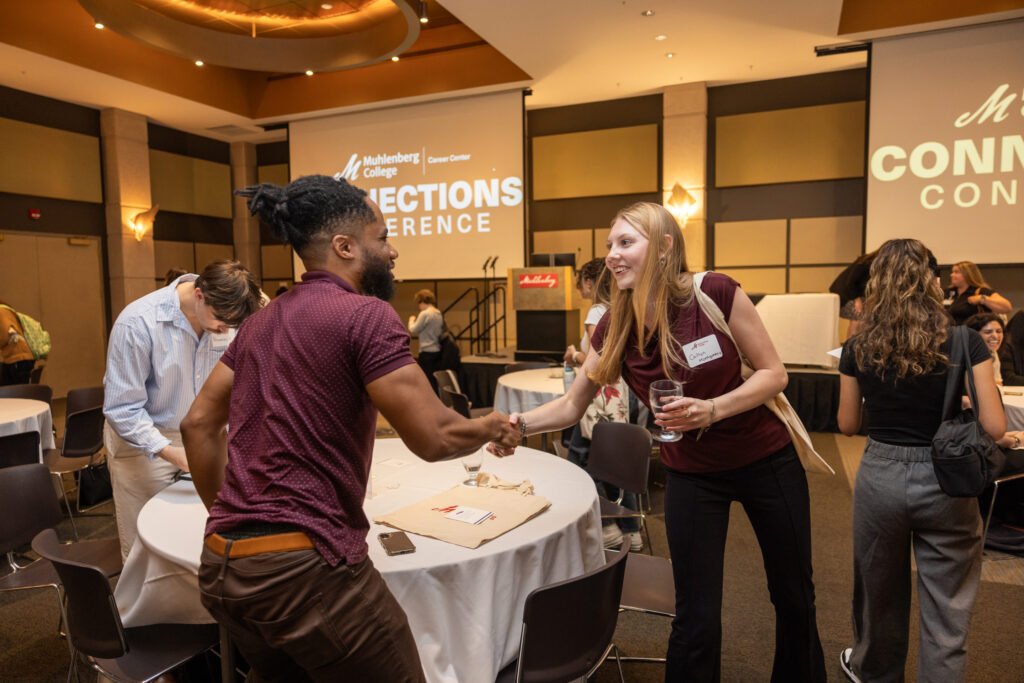 A college student shakes hands with an alumnus at a networking event called the Connections Conference