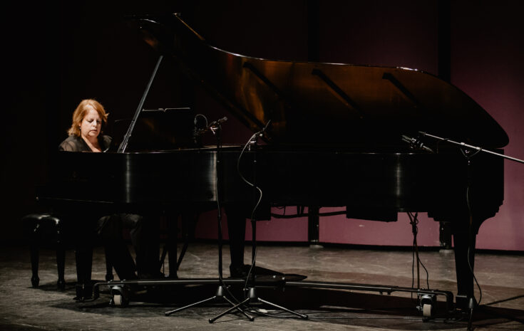 A woman plays a grand piano