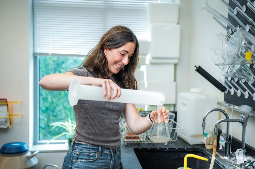 A Muhlenberg student pours liquid into a beaker in a biology lab.