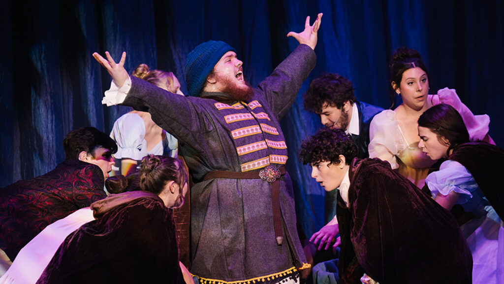 Production photo from Natasha, Pierre and the Great Comet of 1812 shows a group of actors in 19th century Russian dress. The central figure has his arms raised.