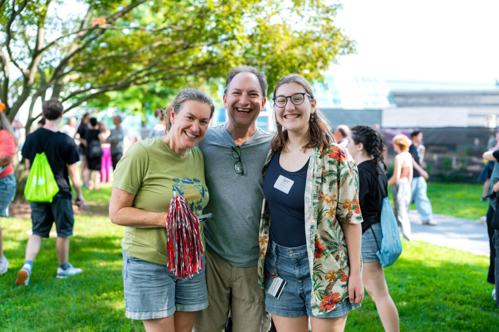 Two Muhlenberg College parents smile for a photo with their student on move-in day
