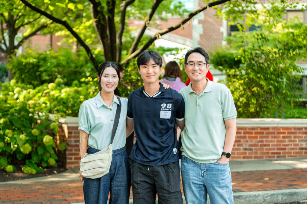 Two Muhlenberg College parents in light green shirts pose with their student during orientation