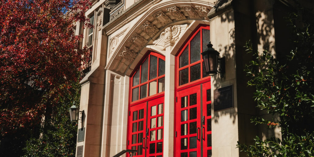 Two red doors on the front of a college building