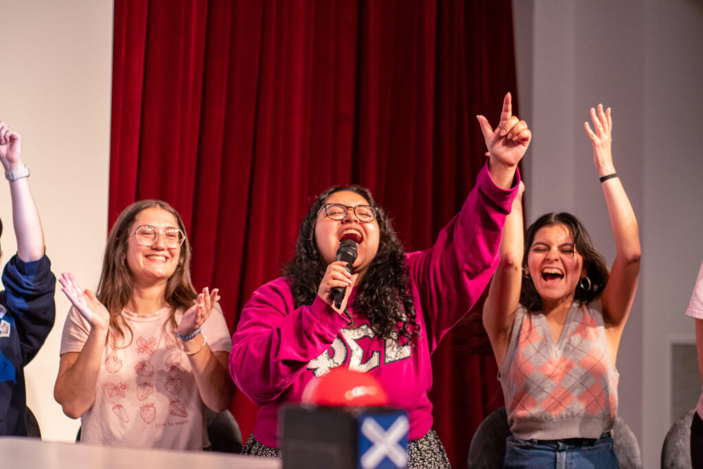 A college student shouts into a microphone and points into the air