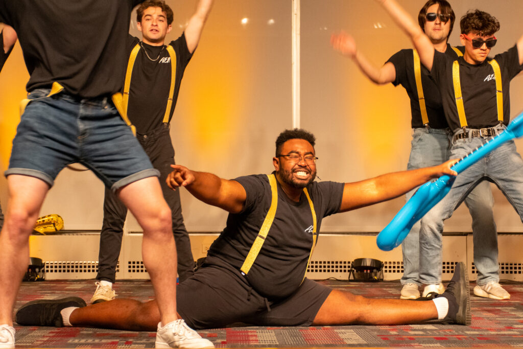A college student does a split and smiles during a lip synching performance