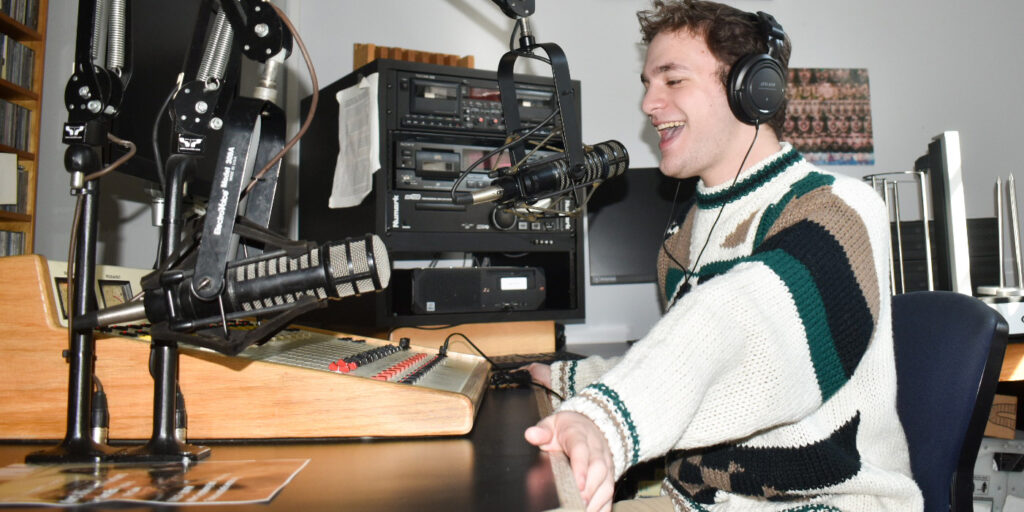 A college student speaks into a microphone in a radio studio