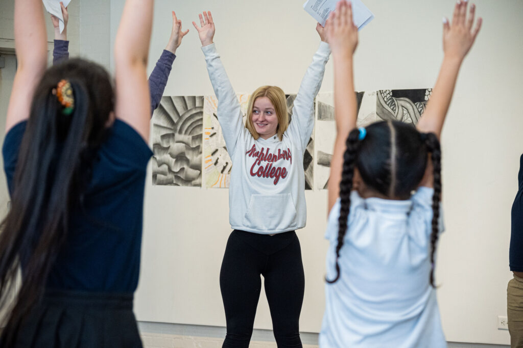 A college student leads elementary school students in a stretch